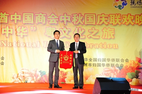 广州市侨联主席李瑜与阿联酋广东商会会长张钦伟在联欢晚会上互赠锦旗